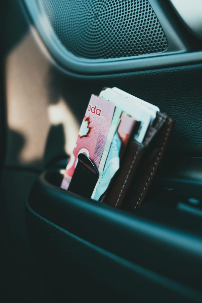 Close-up of a wallet with Canadian currency in a car interior.